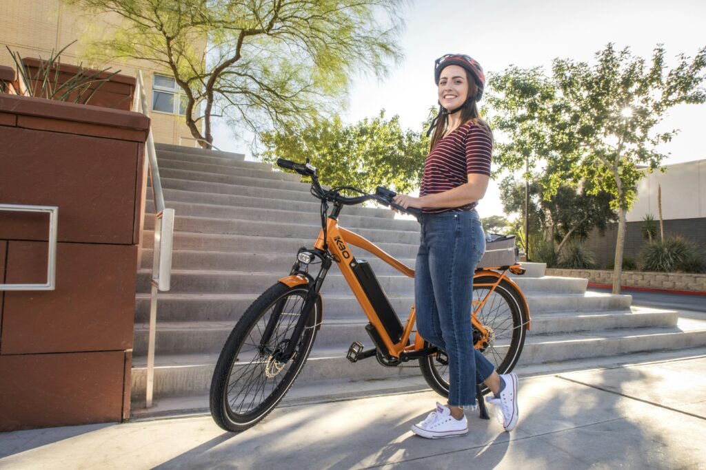 woman in white and black striped long sleeve shirt and blue denim jeans riding orange bicycle woman in white and black striped long sleeve shirt and blue denim jeans riding orange bicycle