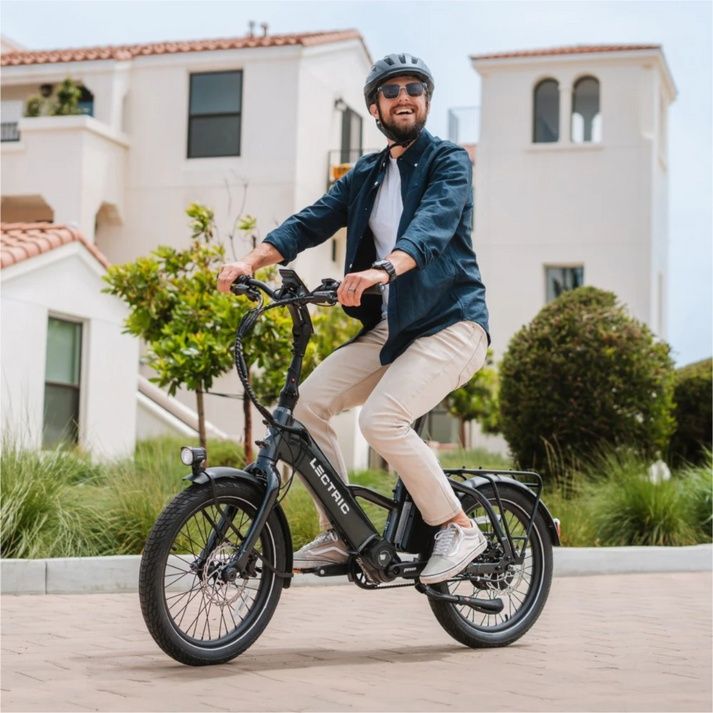 Helmeted rider on a black Lectric ONE outside white buildings Helmeted rider on a black Lectric ONE outside white buildings