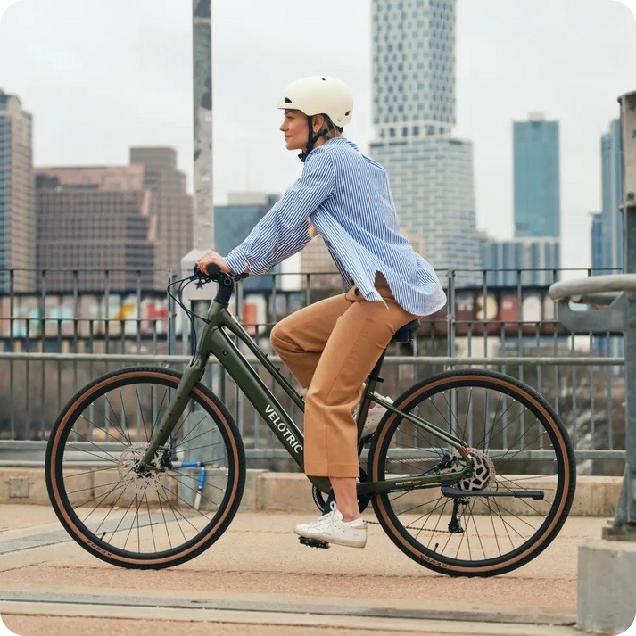 Helmeted rider on a green Velotric Tempo Mid-Step in a manufacturer city photograph Helmeted rider on a green Velotric Tempo Mid-Step in a manufacturer city photograph